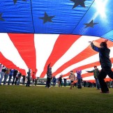 Photo of large flag unfurled across the Grainger Stadium infield during the National Anthem prior to opening game