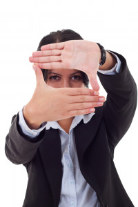 business woman looking through a hand frame over white