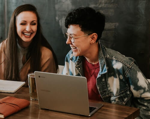 Two happy women in front of a laptop.