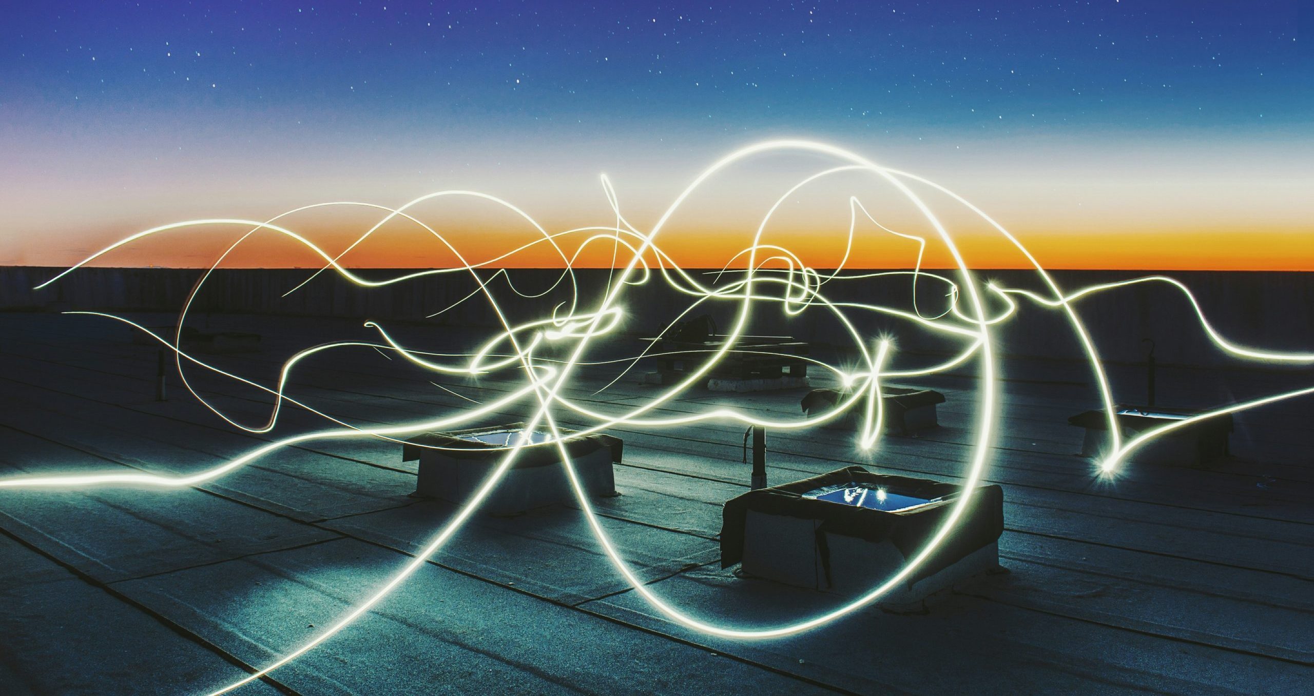 swirls that could be electricity touching down on boxes with screens, sunset in the distance
