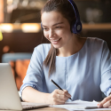 Woman at computer taking notes.