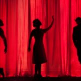 silhouettes of three people on a stage