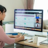 Woman in meeting, sitting at computer.